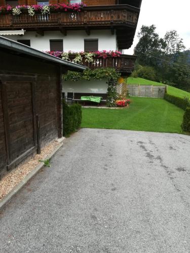 a driveway of a house with a balcony with flowers at Ferienwohnung Familie Fiechtl in Fügenberg