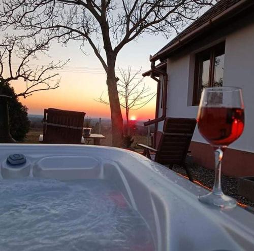 a glass of wine next to a hot tub with a glass of wine at Hajnal Apartman Szigetvár in Szigetvár