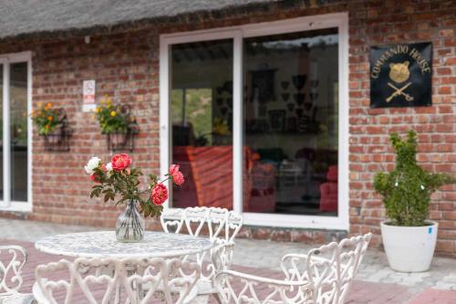 a table and chairs with a vase of roses on it at StayVista at Brickwood Hill with Outdoor Infinity Pool & Jacuzzi in Chandīgarh