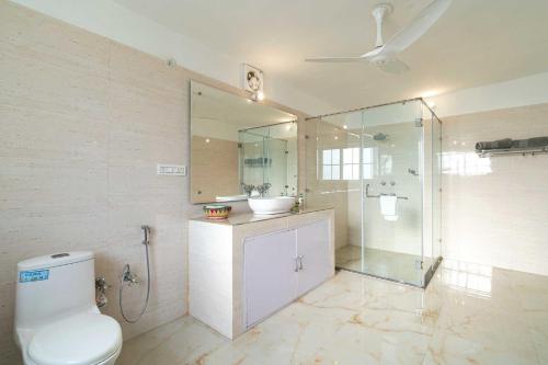 een badkamer met een toilet, een wastafel en een douche bij StayVista at Brickwood Hill with Outdoor Infinity Pool & Jacuzzi in Chandīgarh