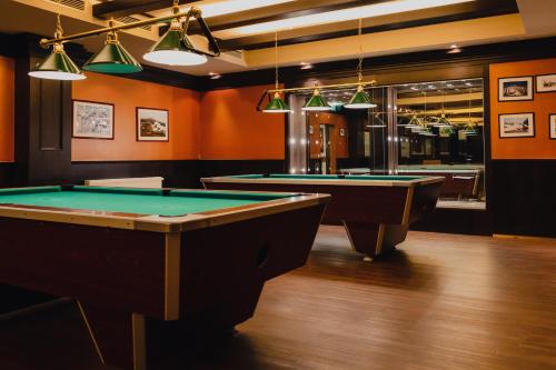 two pool tables in a room with orange walls at Relax Resort Hotel Kreischberg in Sankt Georgen ob Murau