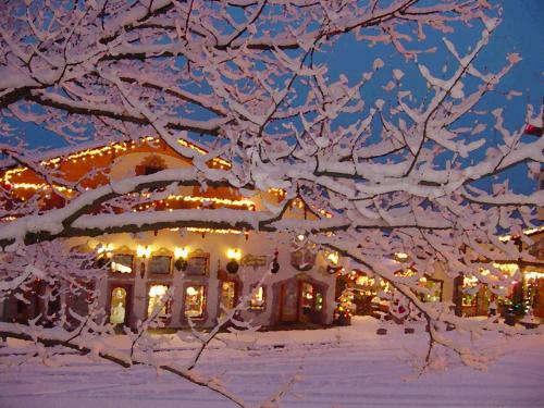 a snow covered tree in front of a house with lights at Linderhof Inn in Leavenworth
