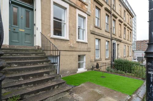 a building with a green door and a grass yard at Renfrew Residence Central Glasgow 4-Bed Flat in Glasgow
