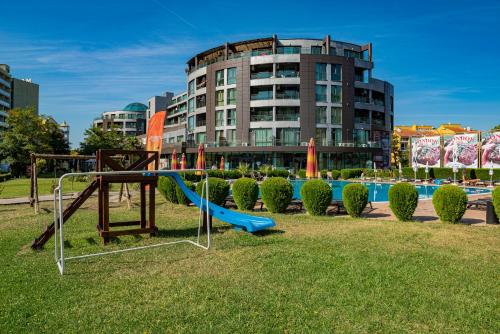 un parque infantil con un tobogán en un parque con un edificio en Menada Sunny Beach Plaza Apartments, en Sunny Beach