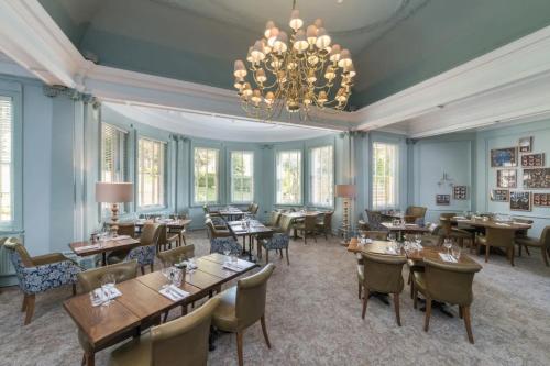 a dining room with tables and chairs and a chandelier at Lansdown Grove Hotel in Bath