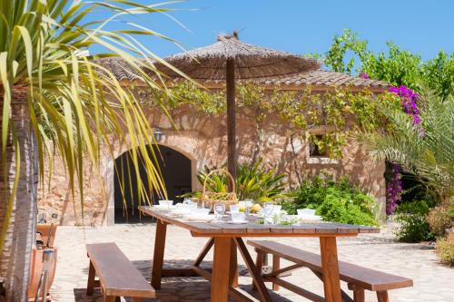 a wooden table in front of a building with an umbrella at Finca Cabana-Barcelo in Caʼs Concos