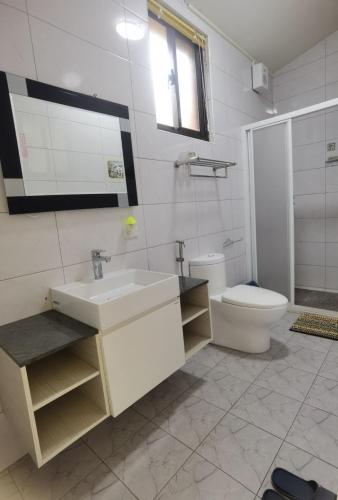 a white bathroom with a sink and a toilet at Kinmen Huquian 58 in Jinhu