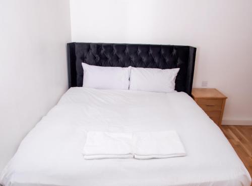 een slaapkamer met een wit bed met een zwart hoofdeinde bij Neptune Apartments in Leeds