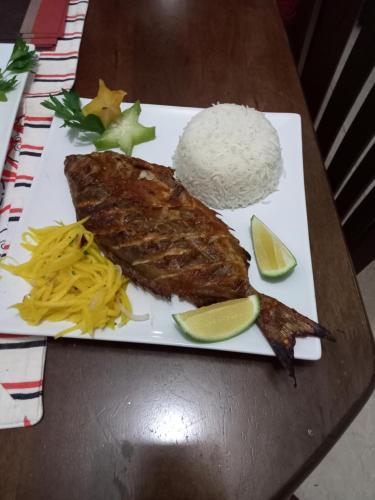 a plate of food with rice and meat and lime slices at Precious Residence C in Grand'Anse