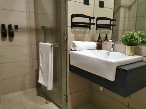 een badkamer met een witte wastafel en een douche bij OPUS RESIDENCE KL I HomeBrickz in Kuala Lumpur