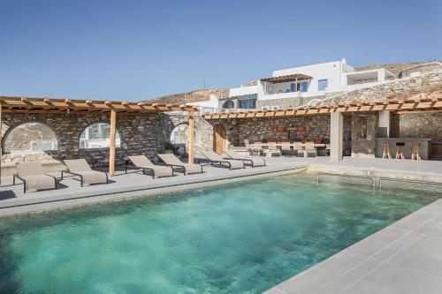 una piscina con tumbonas y una chimenea en Villa Aether - Infinity Pool Villa Mykonos, en Mykonos ciudad