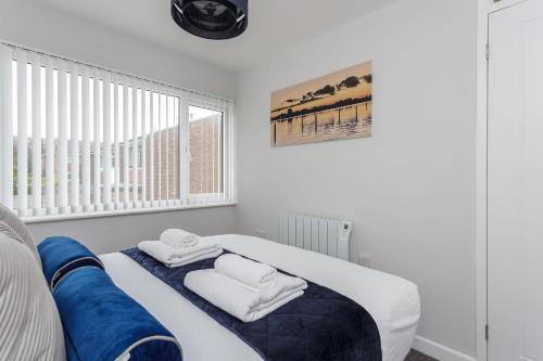 a white room with a bed with towels on it at Castle View - Port Solent Stunning Waterfront House in Portsmouth