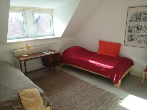 Gästewohnung SEETOR في Lenzen: غرفة نوم مع سرير ومكتب مع بطانية حمراء