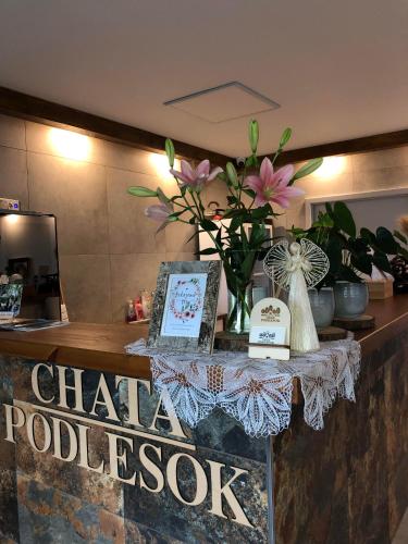 a counter with a vase of flowers on it at CHATA PODLESOK in Hrabušice