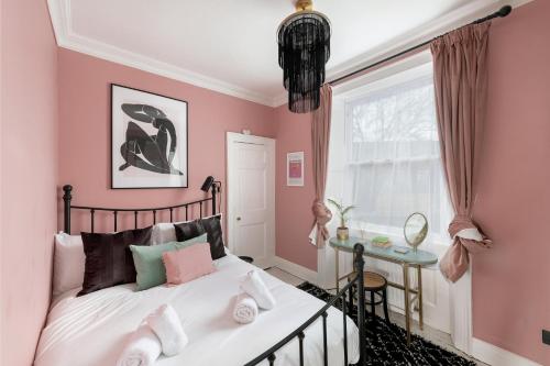 1 dormitorio con paredes rosas, 1 cama y ventana en Stylish Georgian Apartment near the centre of Bath, en Bath