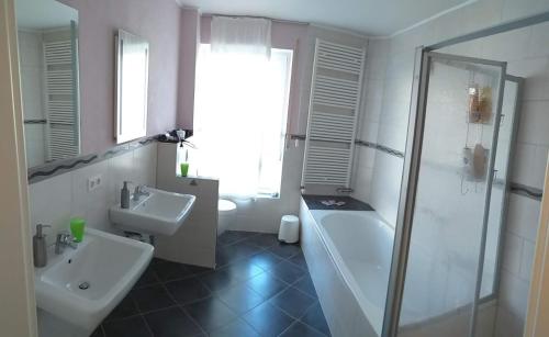 een badkamer met een bad, een wastafel en een douche bij Haus Zangerle in Mettlach