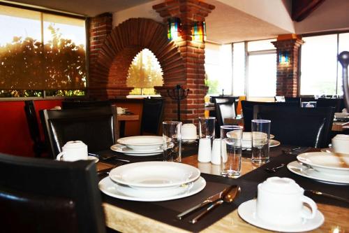 a table with plates and glasses on top of it at Hotel Rinconada de Cortes in Cuernavaca