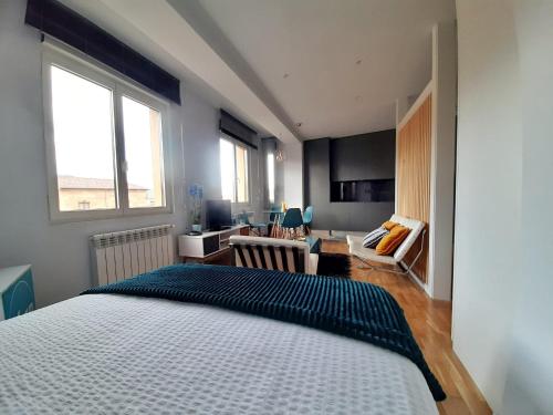 a bedroom with a large bed and a living room at Apartamento Wamba - La Catedral in Oviedo