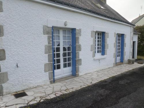 une maison blanche avec une porte et des fenêtres bleues dans l'établissement La Maison bleu, à Saint-Tugdual
