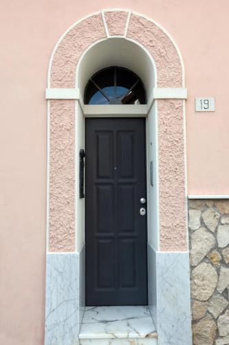 a black door in an archway in a pink building at CASA ANTICA in Gaeta