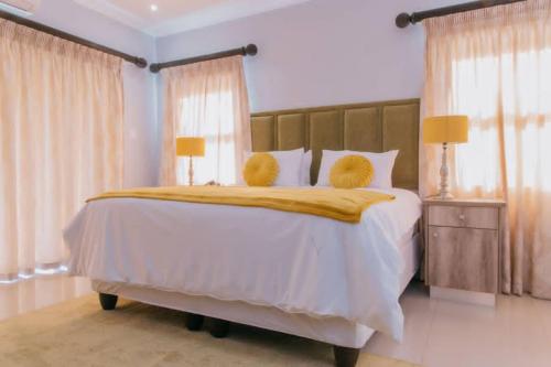 a bedroom with a large white bed with two yellow pillows at Mantenga Hillview in Ezulwini