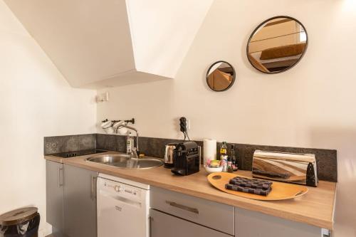 - un comptoir de cuisine avec un évier et un miroir dans l'établissement La Mezzanine d'Au Sans Pareil- Cosy appartement city center Honfleur, à Honfleur
