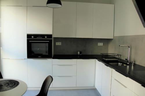 een keuken met witte kasten en een zwart apparaat bij APARTAMENT TETRIS - CENTRUM in Kielce