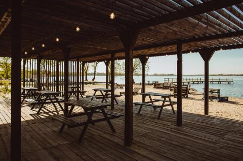 a wooden deck with tables and benches on the beach at Cukrownia Żnin in Żnin