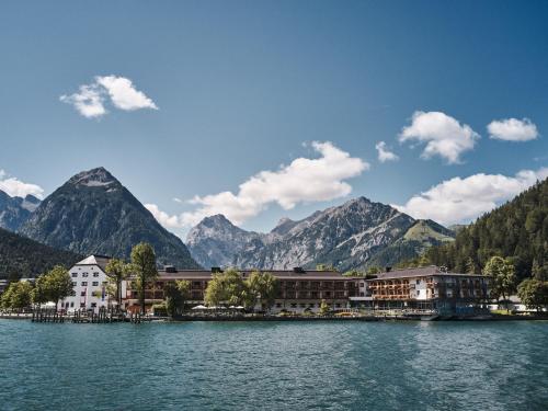 a resort on a lake with mountains in the background at aja Fürstenhaus am Achensee in Pertisau