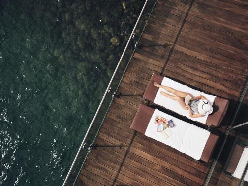 an overhead view of a woman laying on a deck next to the water at aja Fürstenhaus am Achensee in Pertisau