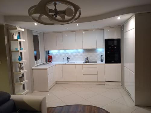 a kitchen with white cabinets and a chandelier at Apartament 35 in Olsztynek