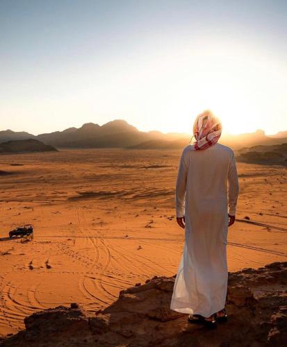 a woman standing in the desert watching the sunset at Wadi Rum Travel camp in Wadi Rum