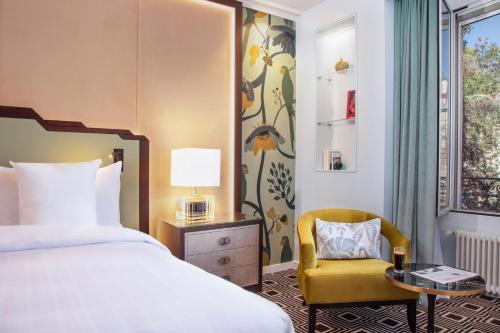 ein Hotelzimmer mit einem Bett und einem Stuhl in der Unterkunft Hotel Bristol in Genf