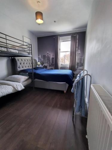 Modern and Spacious flat near Edinburgh في Prestonpans: غرفة نوم بسريرين بطابقين وسرير ازرق