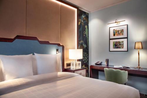 a bedroom with a bed and a desk with a lamp at Hotel Bristol in Geneva