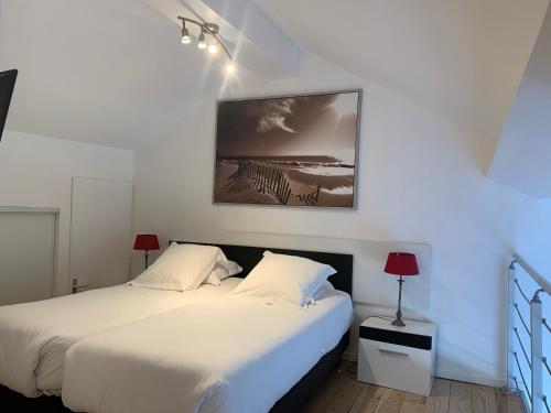 a bedroom with two beds and a painting on the wall at Appartement Du Lac in Hossegor