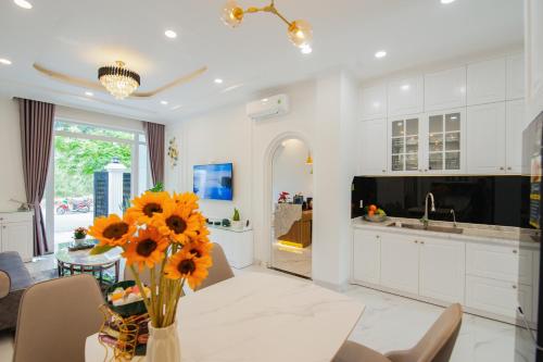 a kitchen with white cabinets and a vase of sunflowers at The View Hotel in Cam Lâm