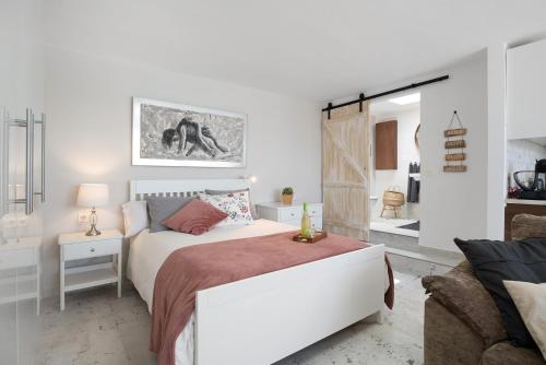 a white bedroom with a bed and a couch at Apartamento El Jable in Arrecife