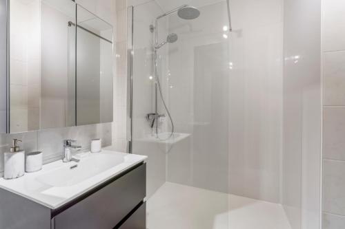 biała łazienka z umywalką i prysznicem w obiekcie Private trendy appartement toplocatie Middelkerke w mieście Middelkerke