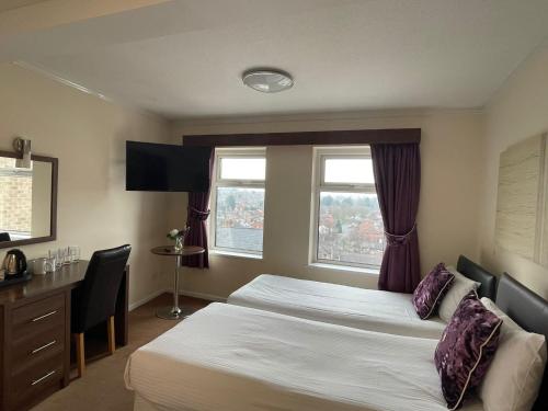a bedroom with two beds and a desk and window at The Continental Hotel, Derby in Derby