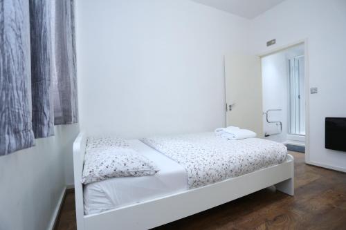 uma cama branca num quarto branco com uma televisão em Gorgeous 2 bedroom 2 bathroom Woolwich em Woolwich