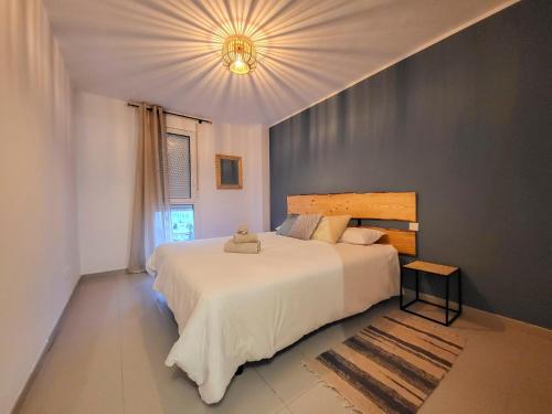 a bedroom with a large white bed and a chandelier at MEDANO4YOU Kevin's Penthouse in El Médano