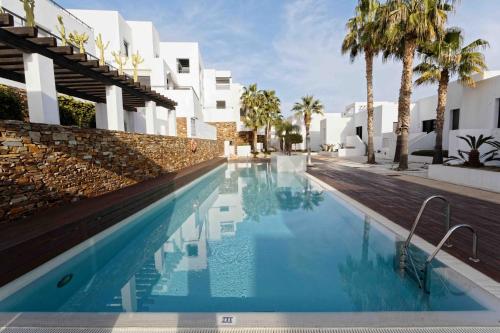 a swimming pool in front of a building with palm trees at SPECTACULAR APRT. IN FRONT OF THE SEA in Mojácar