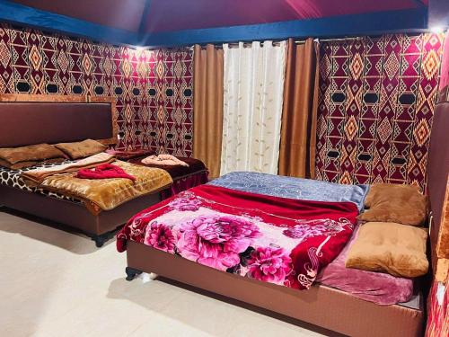 a bedroom with two beds and a wall with wallpaper at Shakria Bedouin Life Camp in Wadi Rum