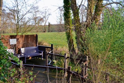 a blue bench sitting on a bridge in a field at Arrowwood Self Catering (Wagtail and Nuthatch) in Kington
