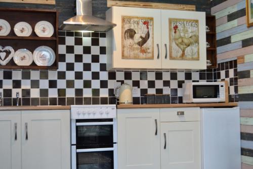 a kitchen with white cabinets and a checkered wall at Arrowwood Self Catering (Wagtail and Nuthatch) in Kington