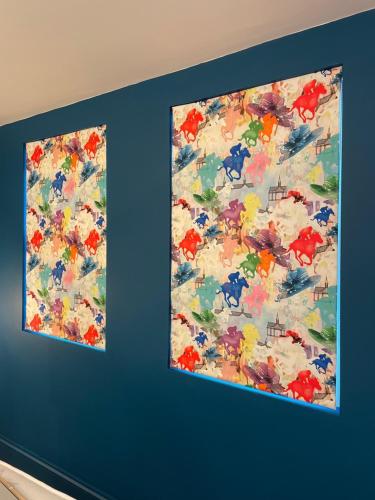 two paintings hanging on a blue wall at Beechurst Serviced Apartments in Cheltenham