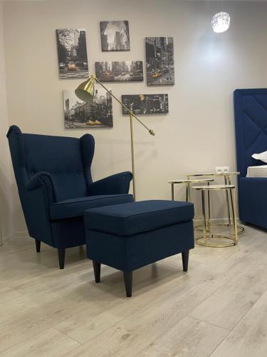 a living room with a blue chair and a lamp at Krivenko 49 Str by StayInn in Pavlodar