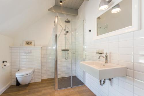 a white bathroom with a sink and a toilet at Lütetsburg Lodges in Lütetsburg