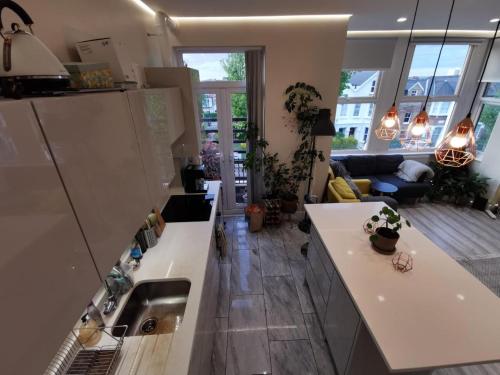a kitchen with white counter tops and a living room at Entire 1-Bed Apartment in London Haringey in London